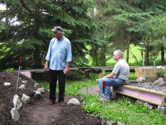 July 16.  Stakes have been placed to indicated the path of a future logging line. To get to the lower level, there will be an 8 percent grade, so this line will operated by geared locomotives, such as the Shay. Ken and Roger study the layout.