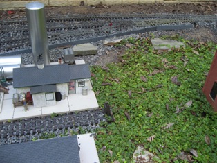 August 27.  I glued some acrylic scraps together at a ninety degree angle and covered one edge with some Precision Products siding. I then put some gravel on top of it, and I have a very quick little retaining wall. 